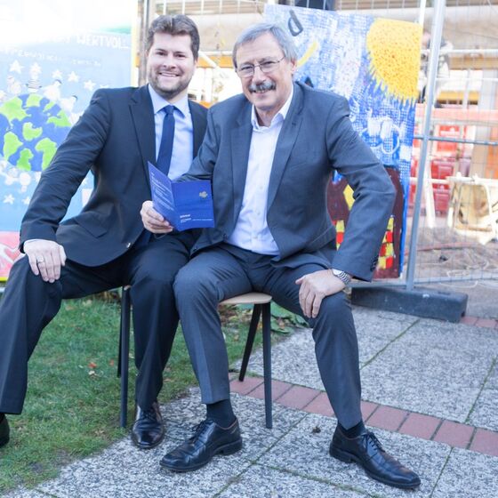 Bezirksbürgermeister Grunenberg und Ratsherr Spiegelhauer testen den neuen Stuhl
