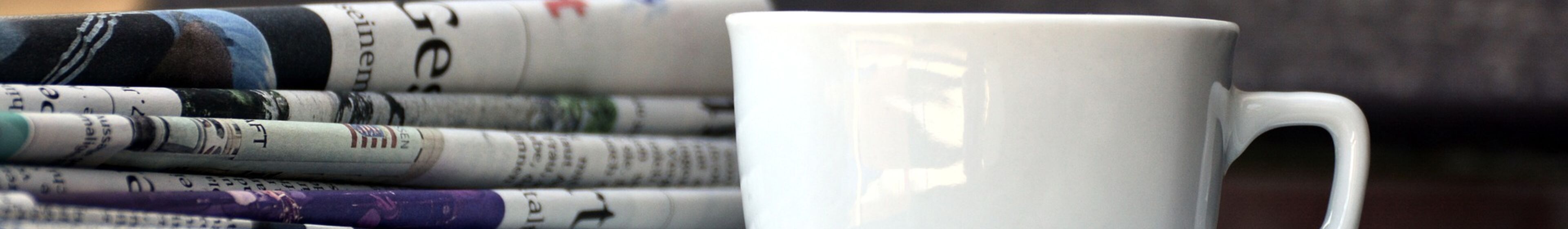 Tasse und Zeitungsstapel