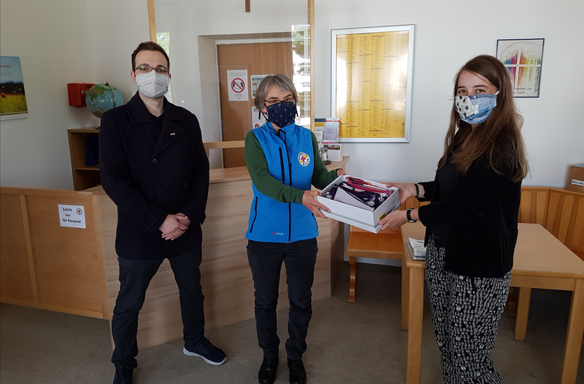 Mitglieder von "Rotaract" bringen selbstgenähte Stoffmasken vorbei.